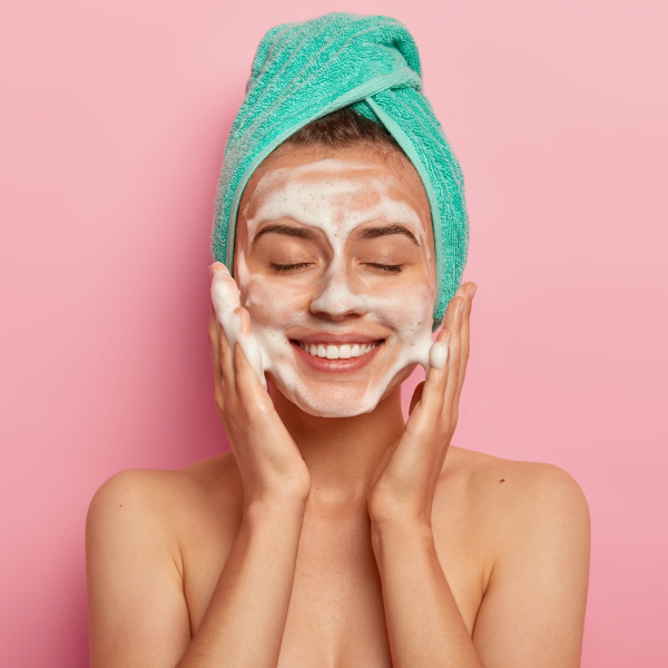 Acne e pelle grassa: primo piano di donna con mousse detergente sul viso - Più Medical