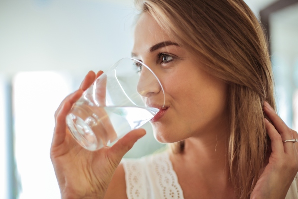 Concept per consigli per la cistite: ragazza beve un bicchiere di acqua doopo aver preso integratori di D-mannosio - Più Medical