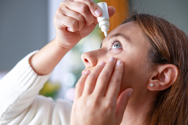 Concept per cura degli occhi: close up donna che applica il collirio