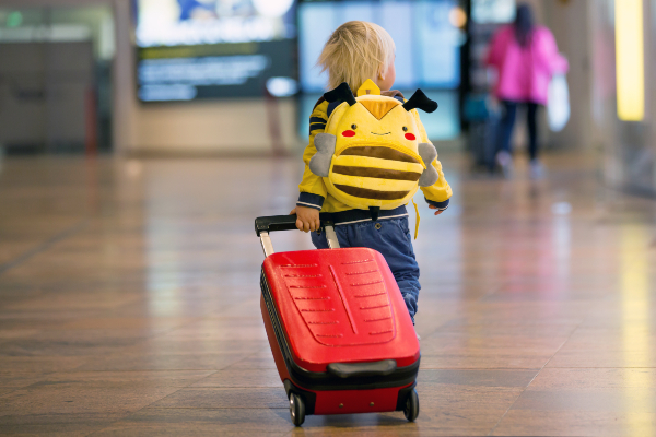 Concept per bambini in viaggio: bambino con zainetto e valigia