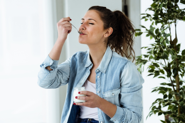 Concept per fermenti lattici: donna mangia uno yogurt