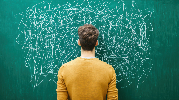Concept per memoria e concentrazione: uomo di spalle mentre guarda una lavagna su cui sono disegnati scarabocchi