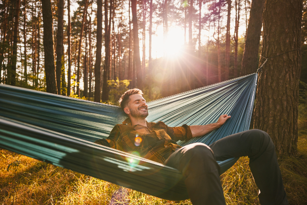 Concept per memoria e concentrazione: giovane uomo in relax su di una amaca in un bosco autunnale