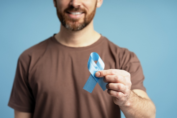 Concept prostata e benessere maschile: uomo tiene in mano un nastro azzurro, simbolo di prevenzione