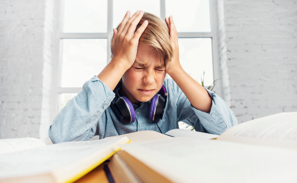 Concept per mal di testa bambini: un adolescente si tiene la testa tra le mani con espressione dolorante
