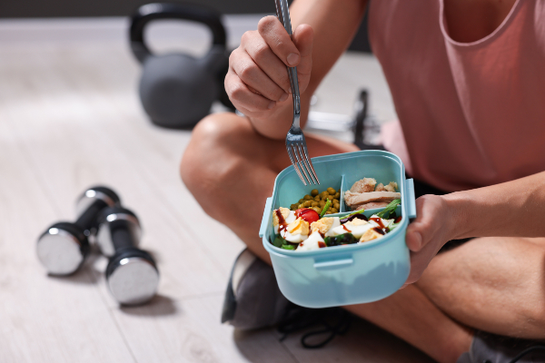 Concept per ripresa dell'attività fisica dopo le vacanze: close up su persona che mangia un pasto equilibrato dopo l'allenamento